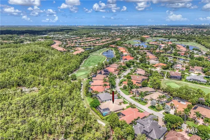 Aerial view of residential area featuring a golf course and a nearby body of water