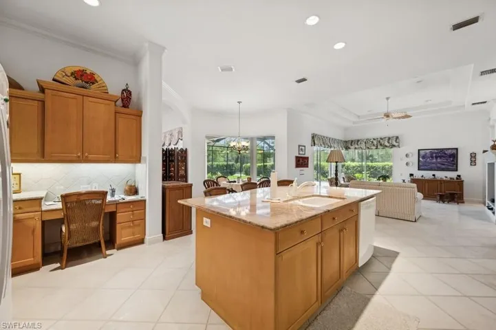 Kitchen with crown molding, tasteful backsplash, dishwasher, open floor plan, and light stone counters