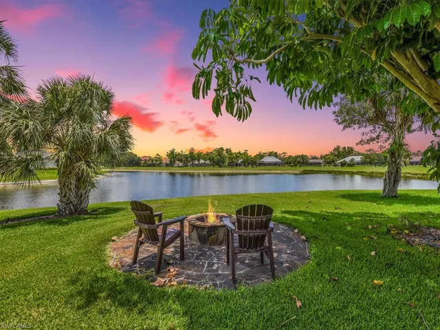 View of grassy yard with an outdoor fire pit and a water view