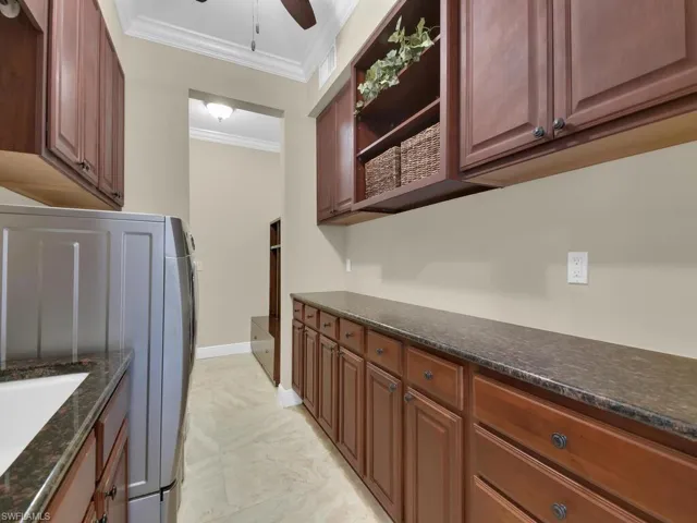 Washroom featuring crown molding, cabinet space, a ceiling fan, and baseboards