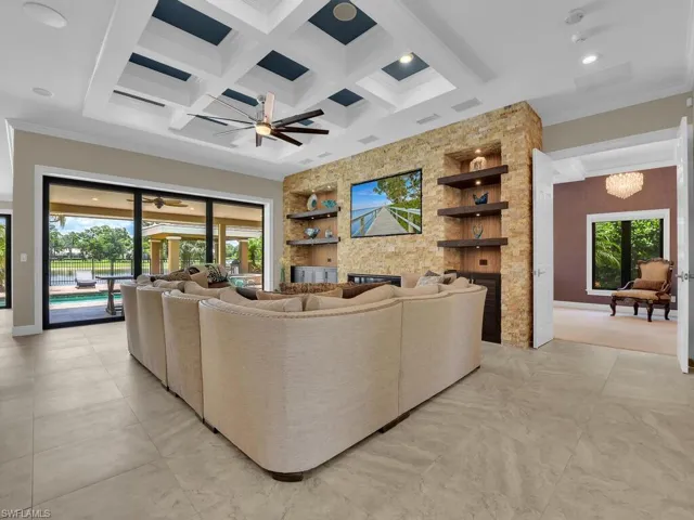 Living area featuring a fireplace, built in shelves, coffered ceiling, ceiling fan, and ornamental molding