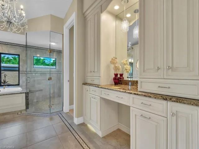 Full bathroom with a chandelier, a stall shower, vanity, and tile patterned flooring