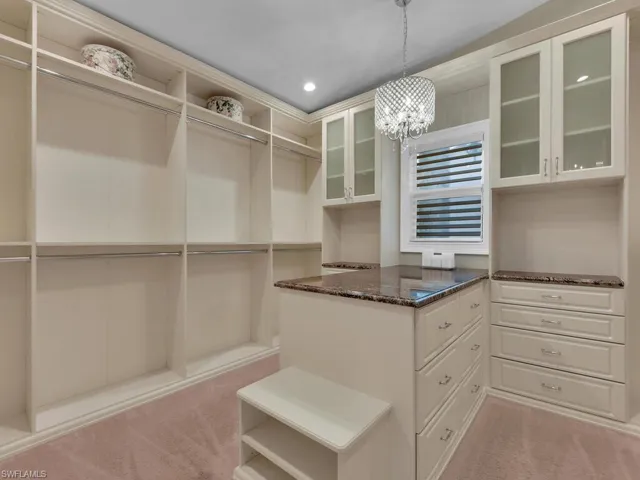 Spacious closet featuring a chandelier and carpet floors