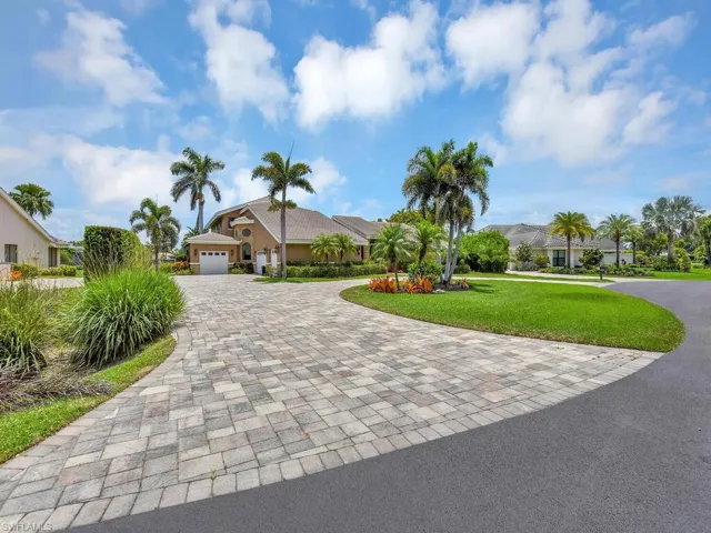 View of front of house featuring decorative driveway, a front yard, and a garage