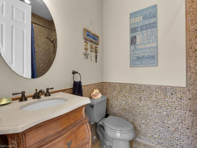 Bathroom with toilet, tile walls, vanity, a wainscoted wall, and a shower with shower curtain
