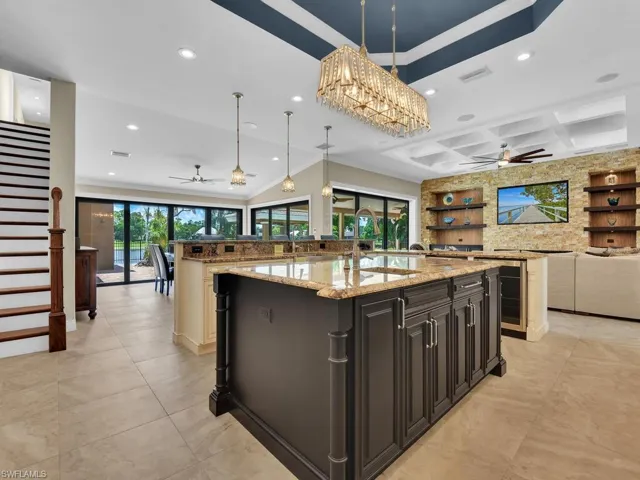 Kitchen with open floor plan, a ceiling fan, a large island with sink, recessed lighting, and crown molding