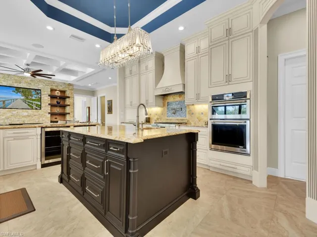 Kitchen featuring premium range hood, wine cooler, a sink, stainless steel double oven, and decorative backsplash