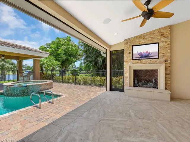 View of patio / terrace with a large fireplace, ceiling fan, and a pool with connected hot tub