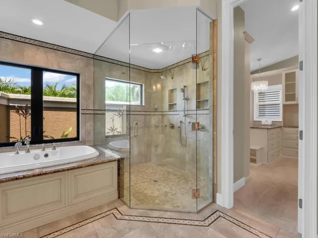 Bathroom featuring a bath, a stall shower, inlaid floor details, baseboards, and recessed lighting