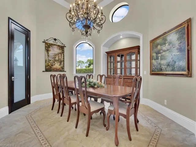 Dining room with inlaid floor details, baseboards, light marble finish flooring, a high ceiling, and a chandelier