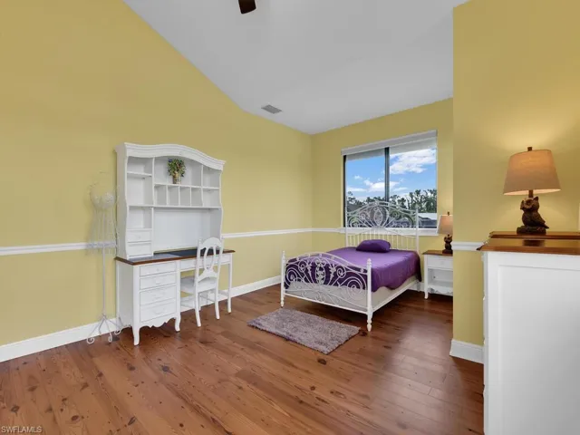 Bedroom featuring wood finished floors, lofted ceiling, baseboards, and a ceiling fan