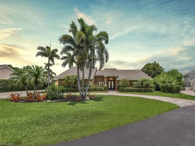 View of front of property with french doors, a lawn, curved driveway, and stucco siding