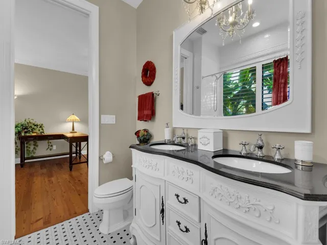 Full bath with a chandelier, a shower, toilet, and double vanity