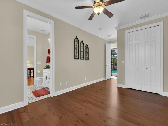 Unfurnished bedroom featuring dark wood-style floors, baseboards, ornamental molding, a ceiling fan, and a closet