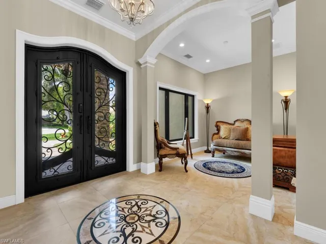 Foyer featuring decorative columns, arched walkways, ornamental molding, baseboards, and french doors