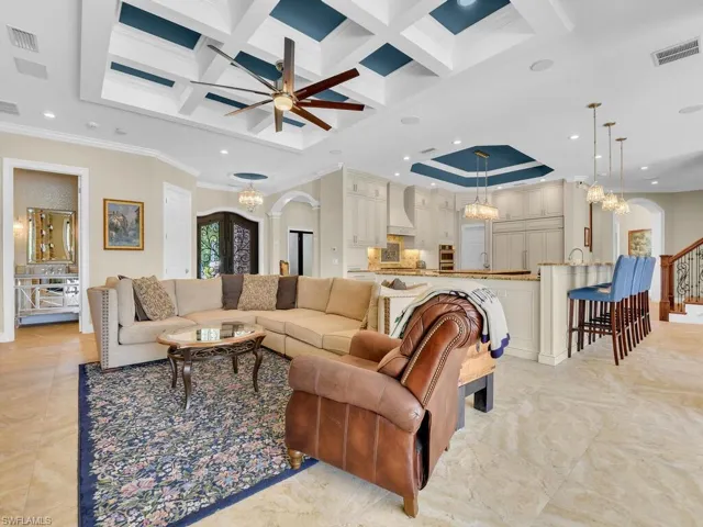 Living area featuring arched walkways, a chandelier, coffered ceiling, ornamental molding, and beam ceiling