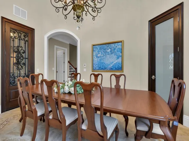 Dining space featuring a chandelier, arched walkways, and stairway