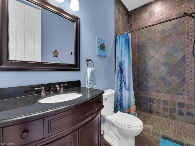 Full bath featuring vanity, toilet, and a tile shower