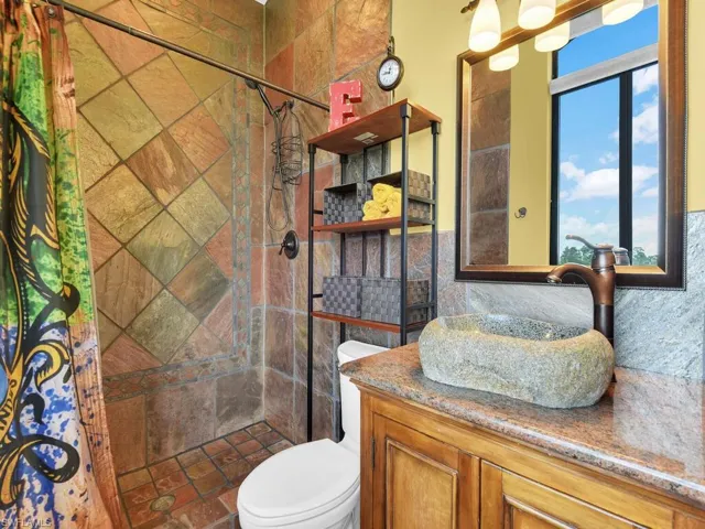 Bathroom featuring vanity, tiled shower, and toilet
