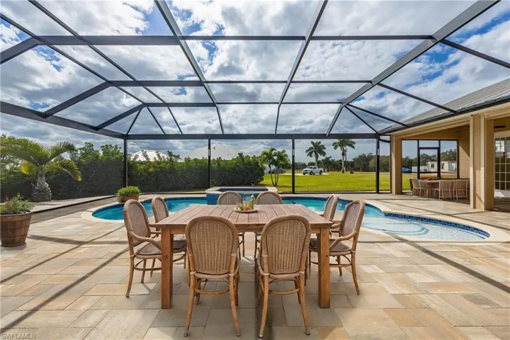 View of swimming pool featuring glass enclosure, a patio area, and exterior bar