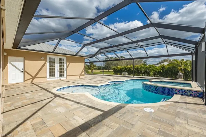 View of pool with an in ground hot tub, french doors, a patio area, and a lanai