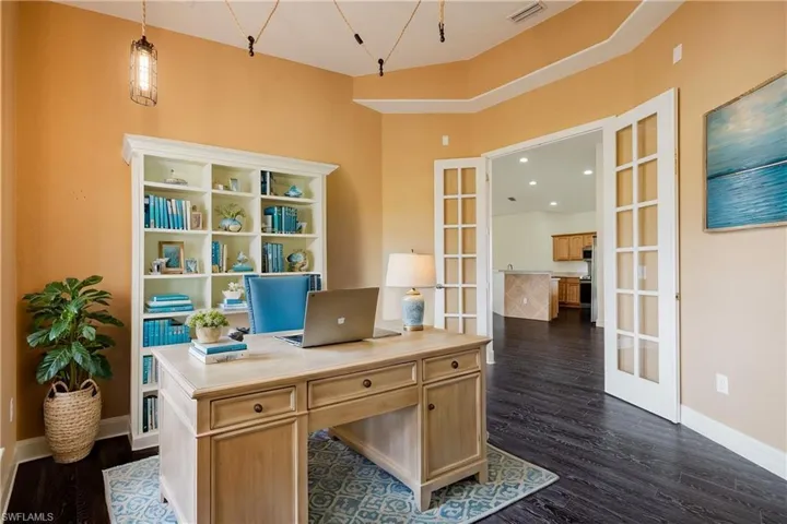 Office featuring dark hardwood / wood-style floors, a towering ceiling, and french doors