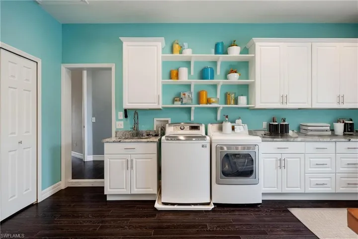 Laundry room featuring cabinets, dark hardwood / wood-style floors, washing machine and dryer, and sink. This is also the bonis room.
