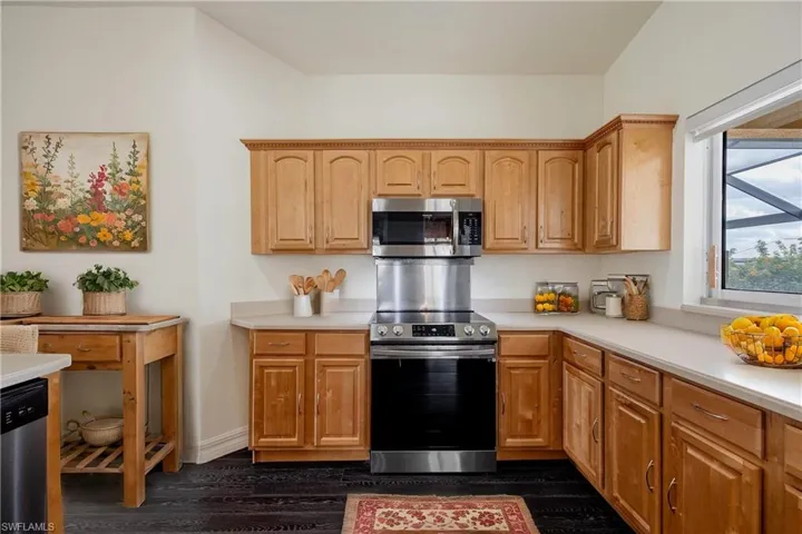 Kitchen with dark hardwood / wood-style floors and appliances with stainless steel finishes