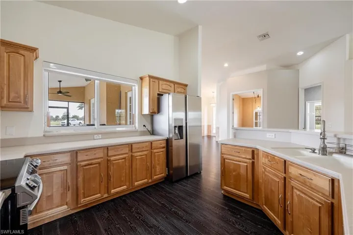 Kitchen featuring a healthy amount of sunlight, stainless steel fridge, dark wood-type flooring, and range