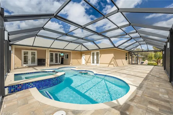 View of swimming pool featuring an in ground hot tub, french doors, a patio area, and a lanai