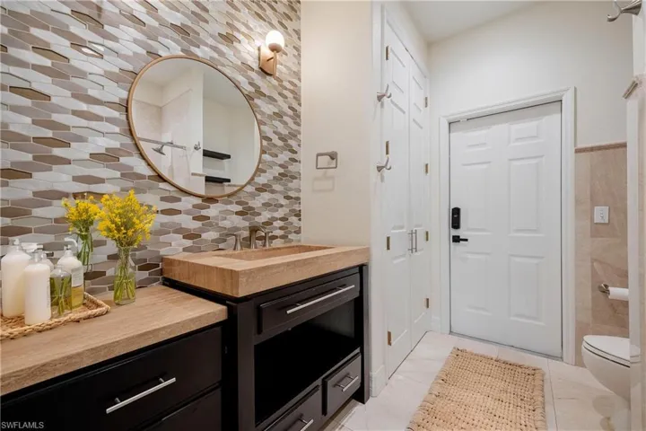 Bathroom featuring backsplash, vanity, tile walls, tile patterned flooring, and toilet - Has access from the pool/lanai area.