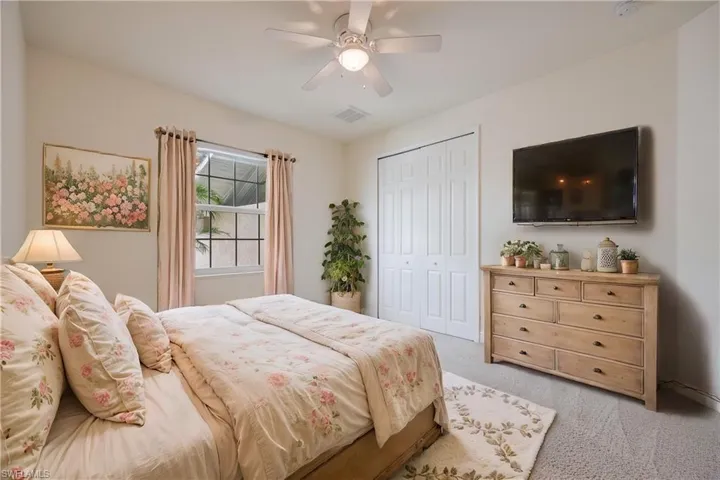 Carpeted bedroom featuring ceiling fan and a closet