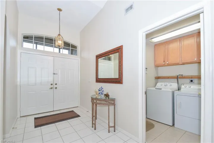 Foyer entrance featuring an inviting chandelier, independent washer and dryer, and light tile patterned floors