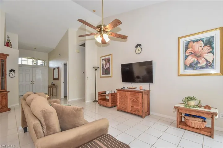 Tiled living room featuring lofted ceiling and ceiling fan