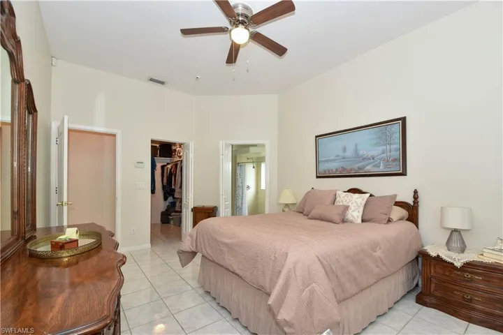 Bedroom featuring ensuite bathroom, a spacious closet, light tile patterned floors, ceiling fan, and a walk-in closet