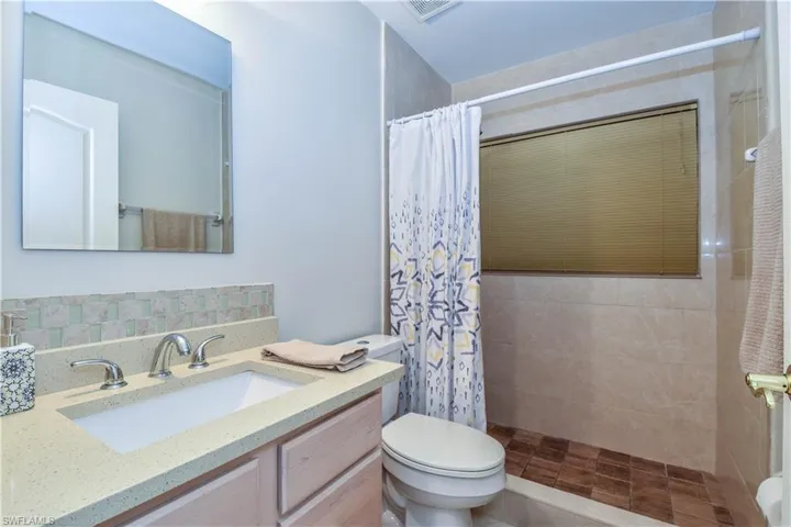 Bathroom featuring a shower with curtain, vanity, and toilet