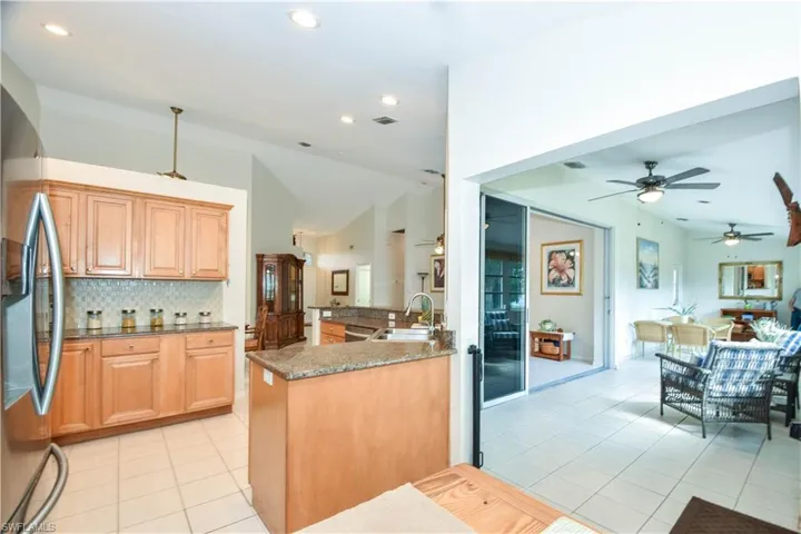Updated Kitchen with Granite countertops, glass backsplash, stainless steel appliancesfloors, stainless steel refrigerator, tasteful backsplash, and vaulted ceiling
