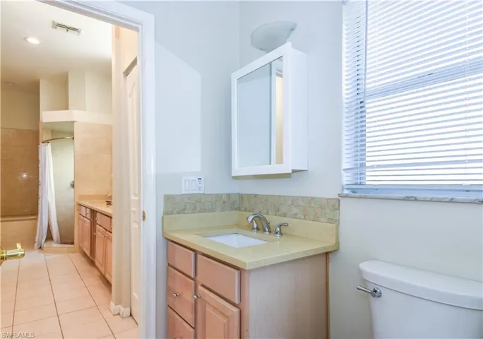 Updated Bathroom with Quartz Counters, Double Sinks, Separate Tub & a shower with curtain, vanity, toilet, and tile patterned flooring