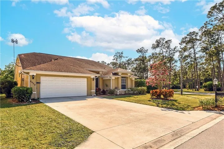 View of front of home with concrete driveway, stucco siding, roof with shingles, an attached garage, and a front lawn