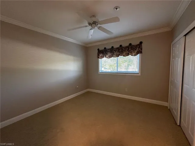 Unfurnished bedroom with ornamental molding, a closet, light colored carpet, and ceiling fan