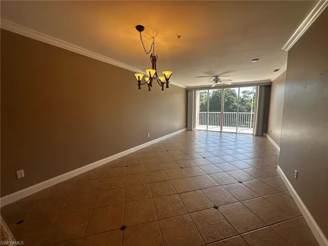 Empty room with ornamental molding, ceiling fan, a chandelier, expansive windows, and tile patterned flooring