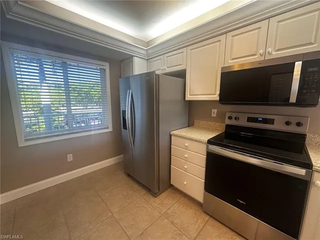 Kitchen featuring stainless steel appliances, light tile patterned flooring, and white cabinetry
