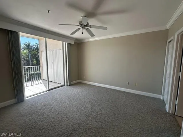 Carpeted spare room with crown molding and ceiling fan