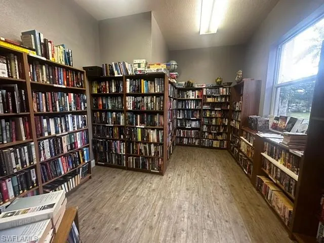 Living area featuring wall of books, a textured ceiling, and light wood-style floors