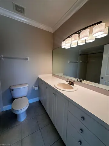 Bathroom featuring ornamental molding, vanity, and dark tile patterned flooring