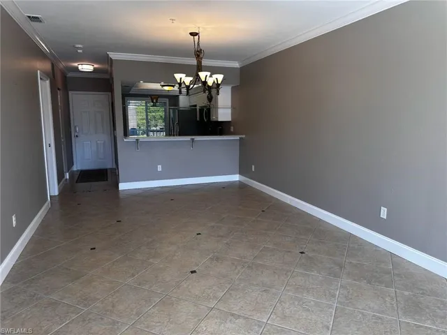 Unfurnished dining area with crown molding, a chandelier, and tile patterned floors