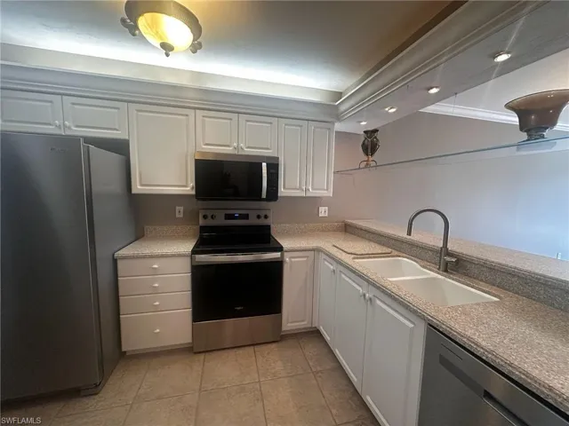 Kitchen with appliances with stainless steel finishes, light stone counters, recessed lighting, white cabinetry, and light tile patterned flooring