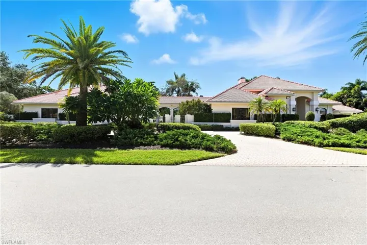 View of front of house featuring decorative driveway, a tile roof, stucco siding, and a chimney
