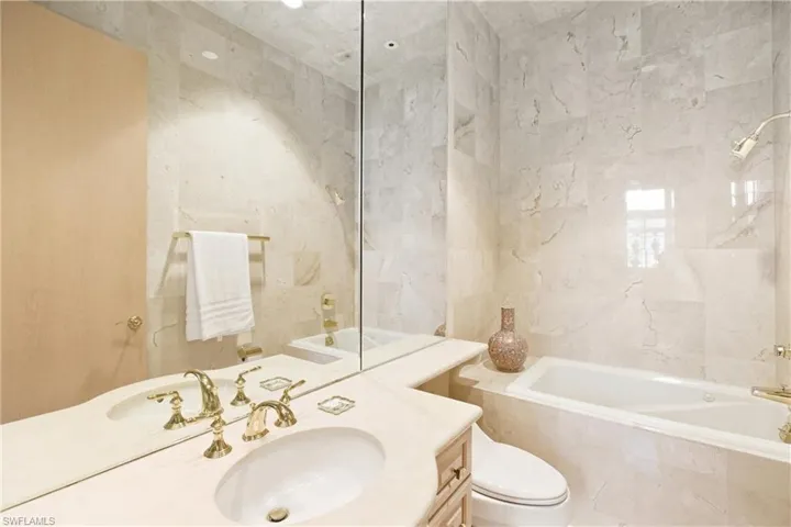 Full bath with vanity, tiled shower / bath combo, and tile walls