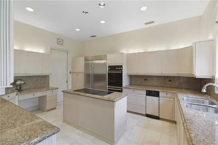 Kitchen with backsplash, light brown cabinetry, recessed lighting, a kitchen island, and built in desk